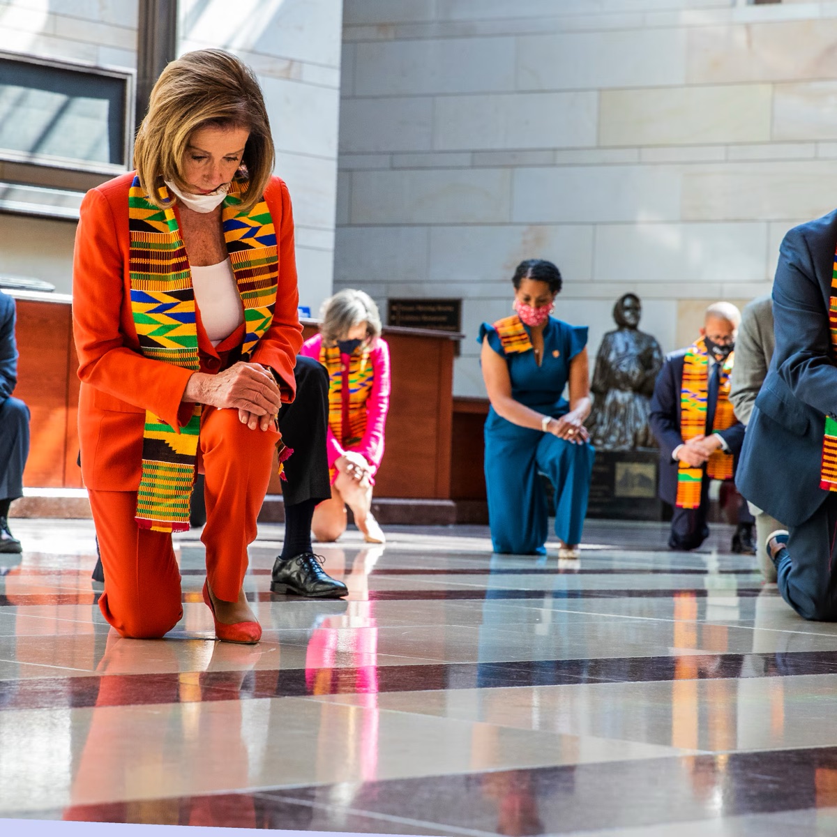 Nancy Pelosi kneeling in kente cloth with members of Congress, June 2020